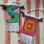 Two small woven pouches with colorful patterns on a striped fabric background
